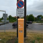 Orangefarbene E-Ladesäule mit Schild für eingeschränktes Parkverbot